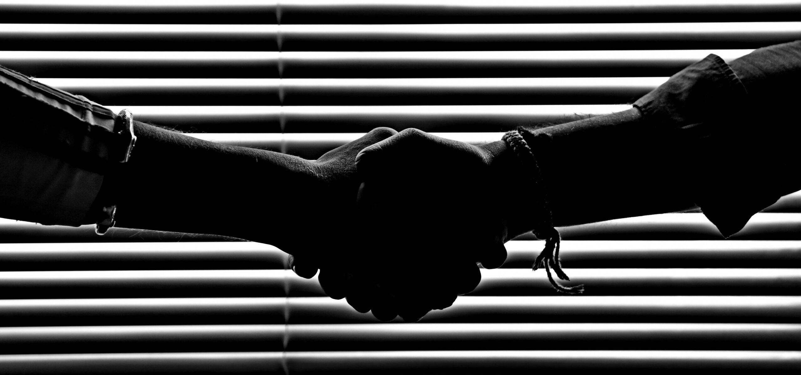 Silhouette of two people shaking hands symbolizing partnership and trust.